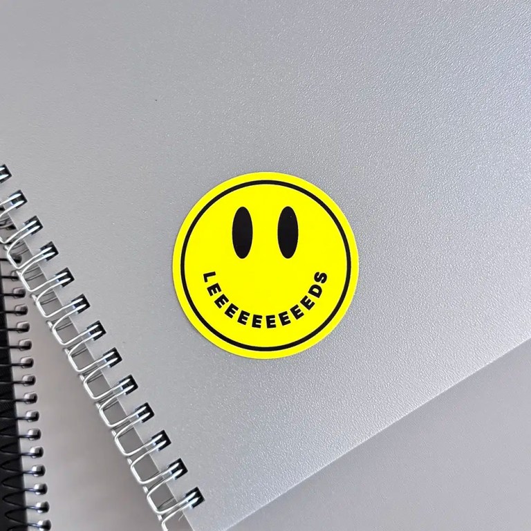 Acid House smiley sticker on a notebook with the word Leeds as its mouth.