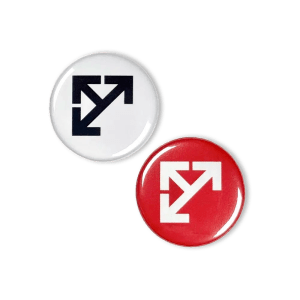 Two Leeds Motorway City button badges: one with the arrow emblem in white on a red background and the other with the emblem in black on a white background.