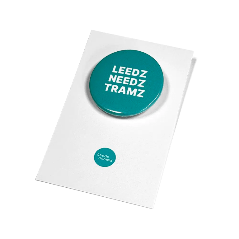 Leedz Needz Tramz white badge on teal coloured backing card.